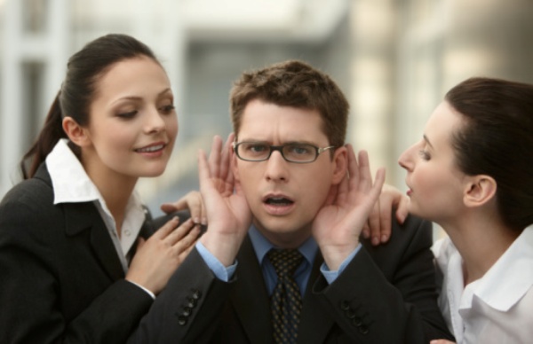 Businessman listening to advice from two woman whispering ear to in the office